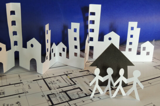 Paper model cityscape on blueprints, highlighting multifamily real estate investing.