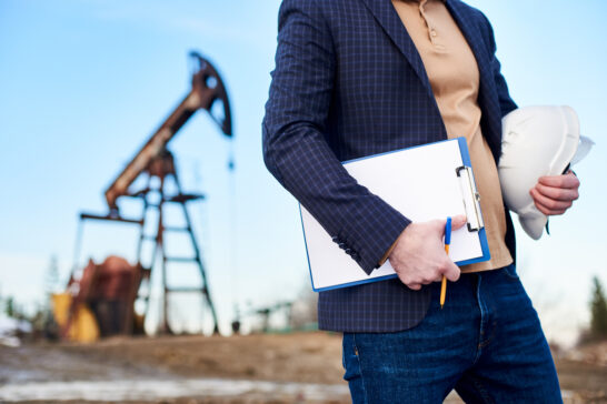 An investor analyzing charts with an oil rig in the background, illustrating Direct Participation Programs in the oil and gas sector, emphasizing tax benefits and risk-reward balance.